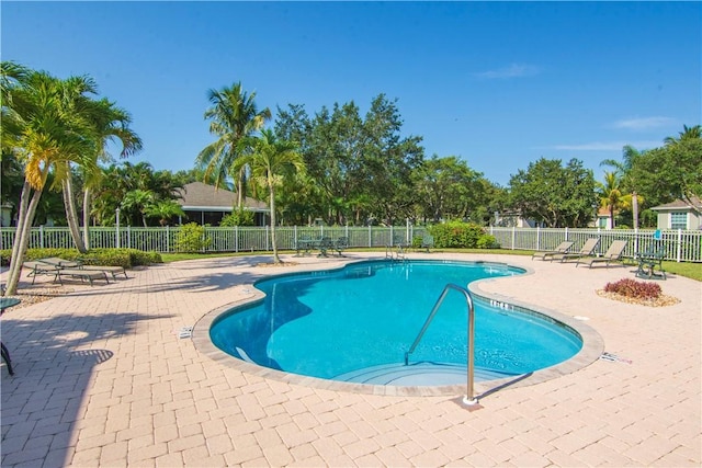 community pool with a patio and fence