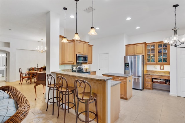 kitchen featuring kitchen peninsula, appliances with stainless steel finishes, a kitchen breakfast bar, light stone countertops, and decorative light fixtures