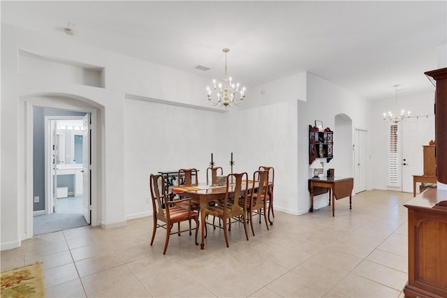 dining area featuring arched walkways, a chandelier, light tile patterned flooring, and baseboards
