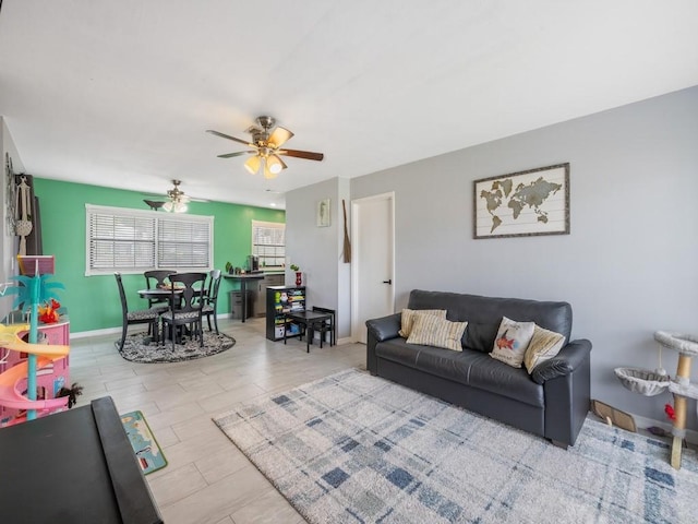 living area featuring ceiling fan and baseboards