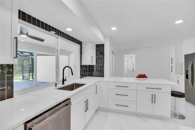 kitchen with white cabinets, marble finish floor, light stone countertops, stainless steel appliances, and a sink