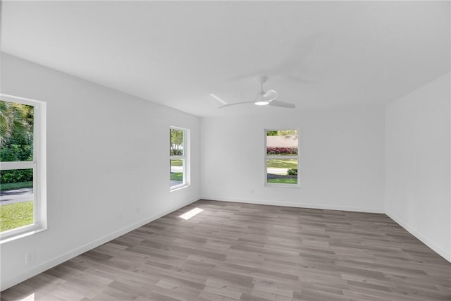 spare room with wood finished floors, a ceiling fan, and baseboards