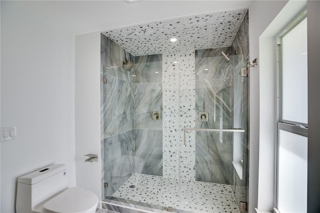 bathroom featuring toilet and a marble finish shower