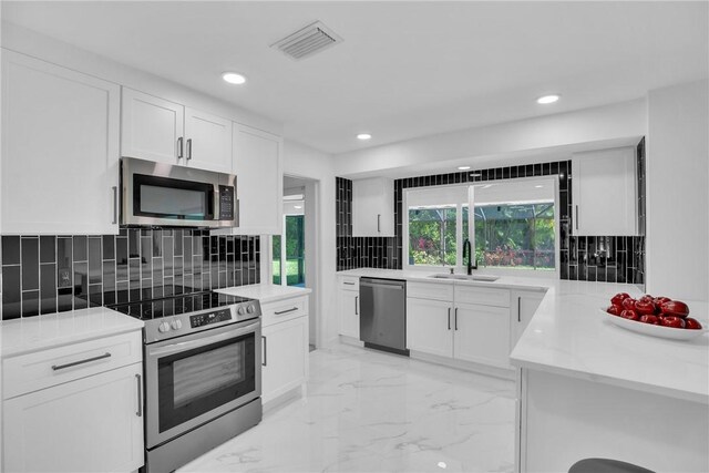 kitchen with tasteful backsplash, visible vents, appliances with stainless steel finishes, white cabinetry, and a sink