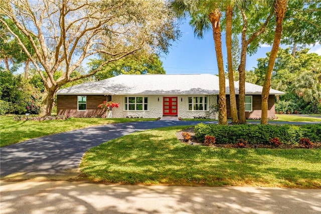 ranch-style home featuring driveway, french doors, and a front yard