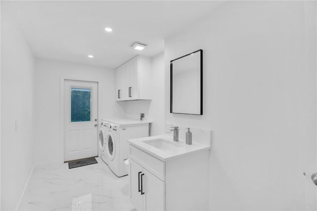 washroom featuring marble finish floor, washer and clothes dryer, cabinet space, a sink, and baseboards