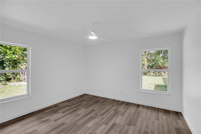 spare room with baseboards and wood finished floors