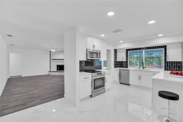 kitchen featuring visible vents, decorative backsplash, marble finish floor, stainless steel appliances, and a sink