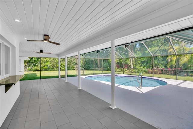 pool with ceiling fan, a patio, a yard, and glass enclosure