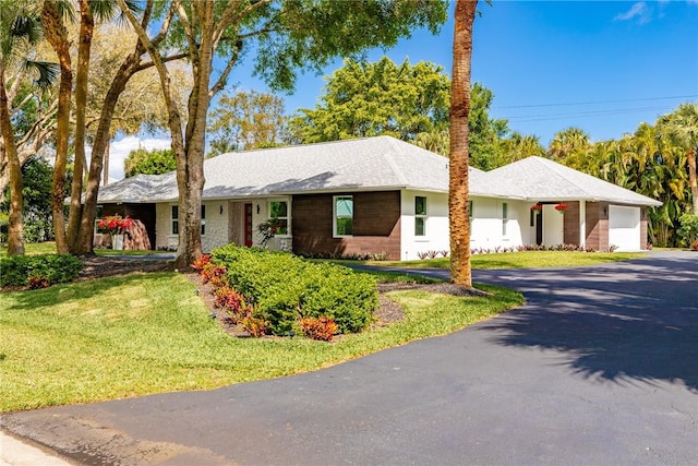 ranch-style house featuring driveway, a front lawn, and an attached garage