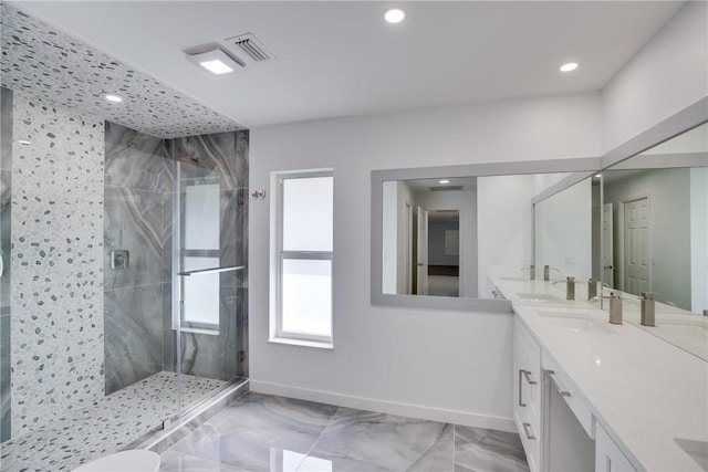 bathroom featuring marble finish floor, double vanity, a sink, a shower stall, and baseboards