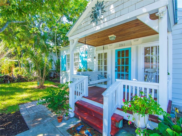 view of exterior entry featuring a yard and covered porch