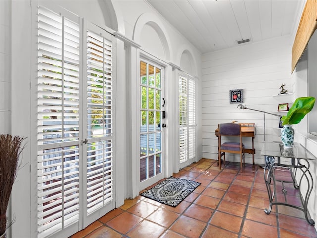 entryway with tile patterned floors and wood walls