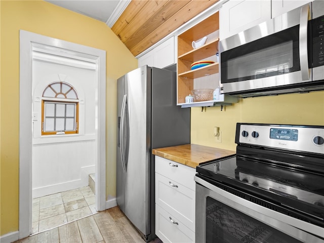 kitchen with lofted ceiling, white cabinets, butcher block countertops, light hardwood / wood-style floors, and stainless steel appliances