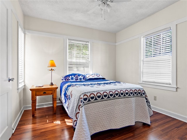 bedroom with a textured ceiling, ceiling fan, and dark wood-type flooring