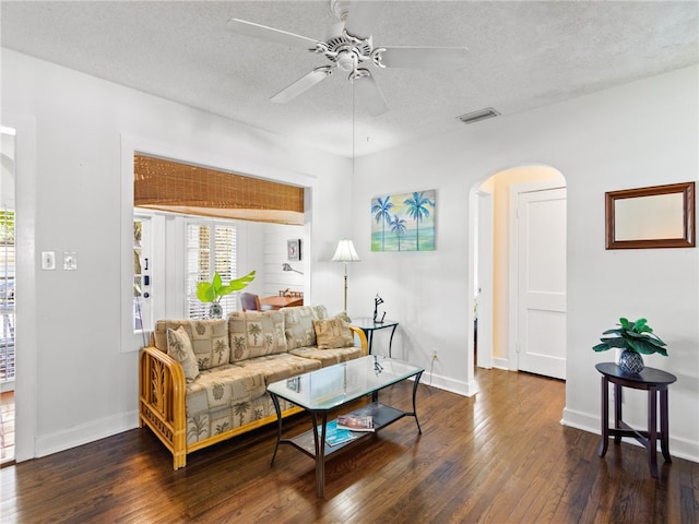 living room with a textured ceiling, dark hardwood / wood-style floors, and ceiling fan