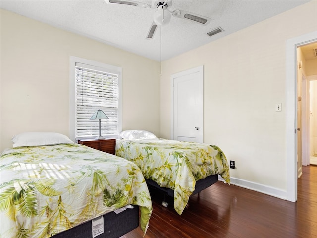 bedroom featuring ceiling fan, dark hardwood / wood-style flooring, and a textured ceiling