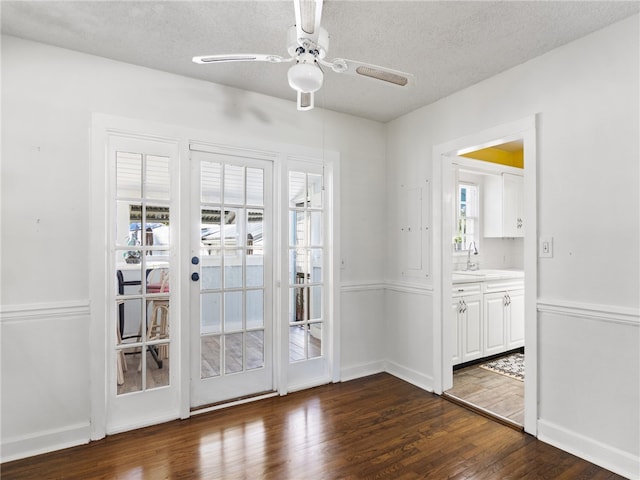 doorway to outside featuring a textured ceiling, dark hardwood / wood-style flooring, and a wealth of natural light