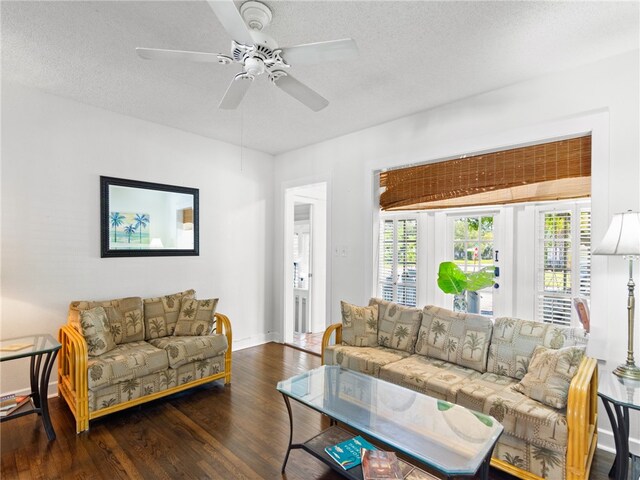 living room with ceiling fan, dark hardwood / wood-style flooring, and a textured ceiling