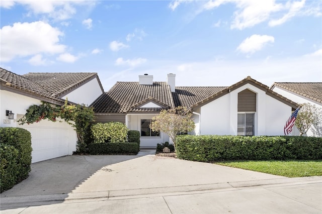 view of front of home featuring a chimney, stucco siding, a garage, driveway, and a tiled roof