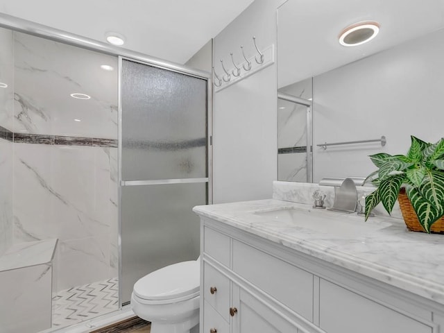 bathroom featuring vanity, hardwood / wood-style flooring, toilet, and a shower with shower door