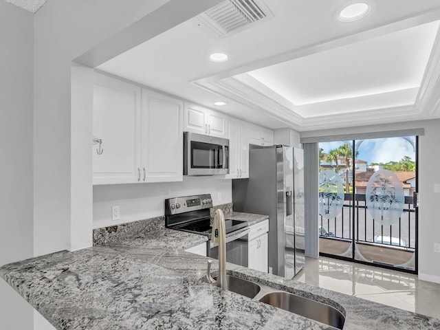 kitchen with white cabinets, a raised ceiling, kitchen peninsula, and appliances with stainless steel finishes