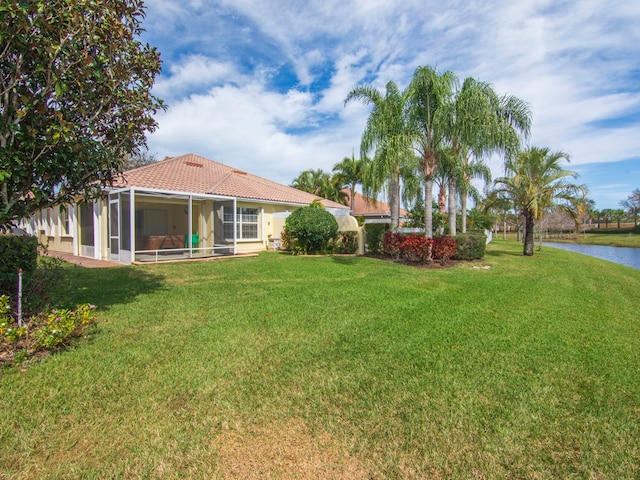 view of yard with a sunroom and a water view