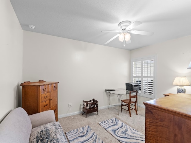 office space with a textured ceiling, light colored carpet, and ceiling fan