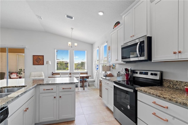 1440 Carriage Ct, Vero Beach, FL 32966 - kitchen featuring stainless steel appliances, vaulted ceiling, white cabinetry, light tile patterned flooring, and light stone countertops