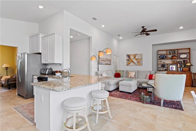 1440 Carriage Ct, Vero Beach, FL 32966 - kitchen with a sink, open floor plan, light stone counters, a ceiling fan, and white cabinets
