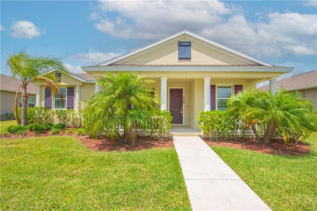 1440 Carriage Ct, Vero Beach, FL 32966 - view of front of house with stucco siding, a porch, and a front lawn