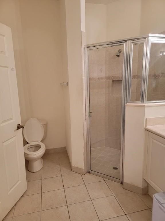 full bath with tile patterned floors, a shower stall, toilet, and baseboards