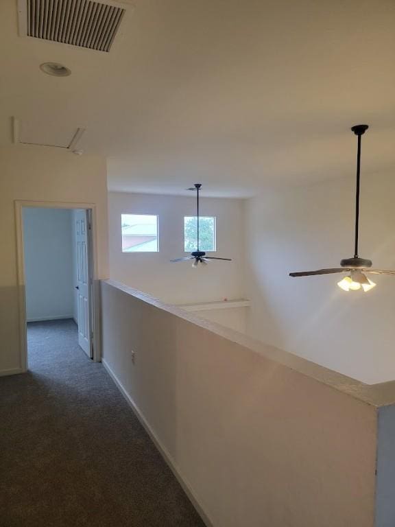 hallway with dark colored carpet and baseboards