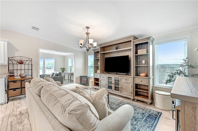 living room featuring light hardwood / wood-style floors, an inviting chandelier, vaulted ceiling, and ornamental molding