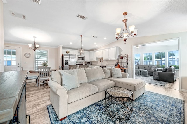 living room with ceiling fan with notable chandelier, crown molding, light hardwood / wood-style flooring, and lofted ceiling