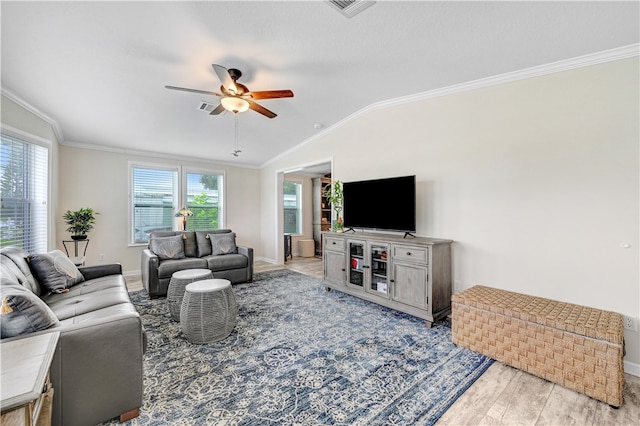 living room with light wood-type flooring, lofted ceiling, a healthy amount of sunlight, and crown molding