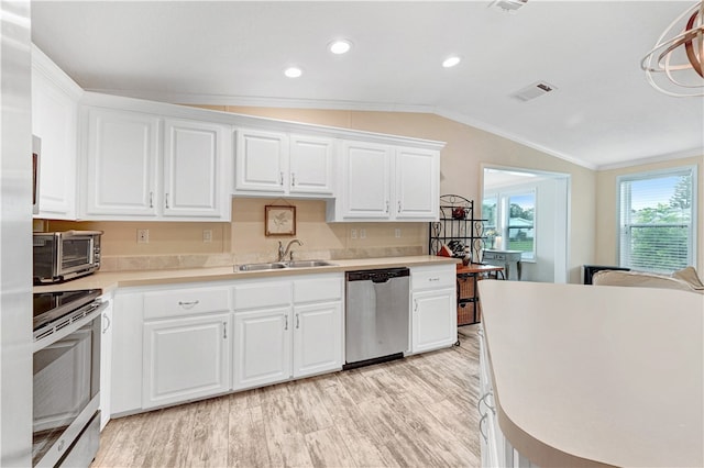 kitchen with white cabinets, vaulted ceiling, sink, and appliances with stainless steel finishes