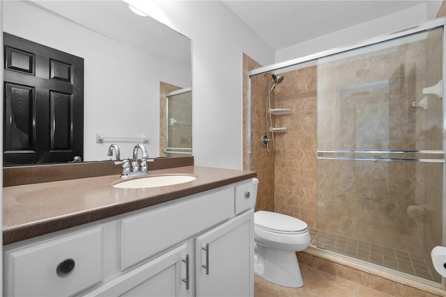 bathroom featuring tile patterned flooring, vanity, an enclosed shower, and toilet