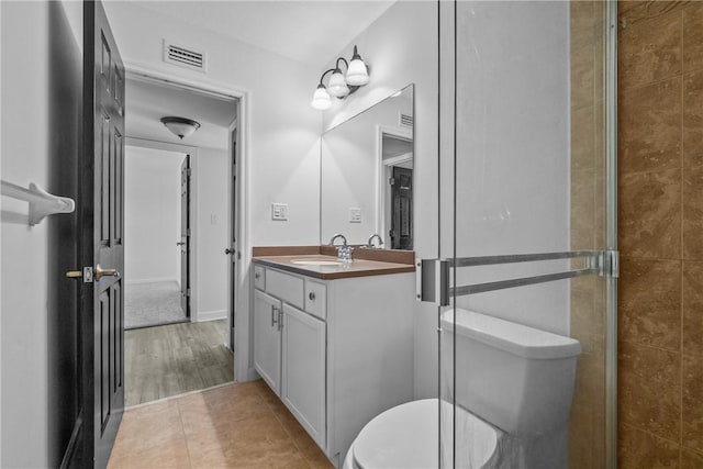 bathroom featuring tile patterned floors, vanity, toilet, and walk in shower