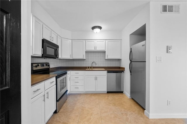 kitchen with white cabinets, sink, decorative backsplash, light tile patterned floors, and stainless steel appliances