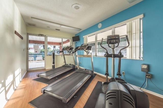 exercise room with a textured ceiling and light hardwood / wood-style flooring