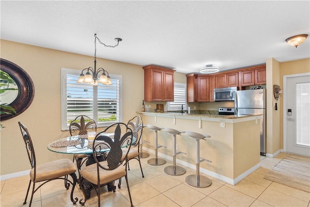 kitchen featuring light tile patterned floors, a peninsula, an inviting chandelier, stainless steel appliances, and light countertops