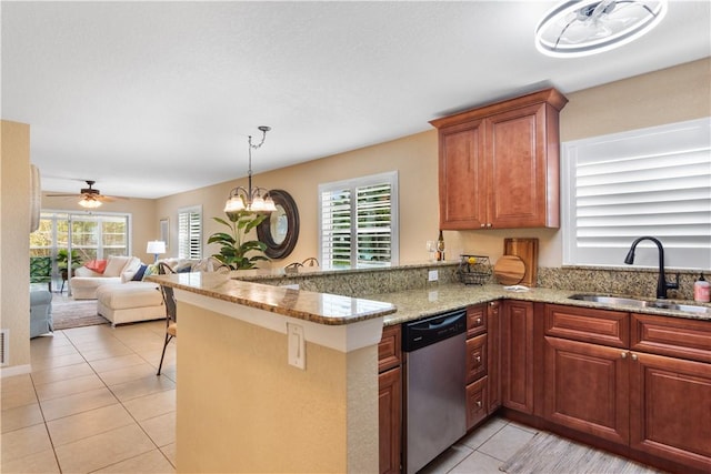 kitchen featuring light tile patterned floors, a peninsula, a sink, stainless steel dishwasher, and light stone countertops