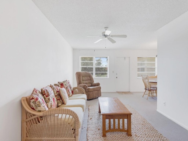 living room with a textured ceiling, carpet flooring, a ceiling fan, and baseboards