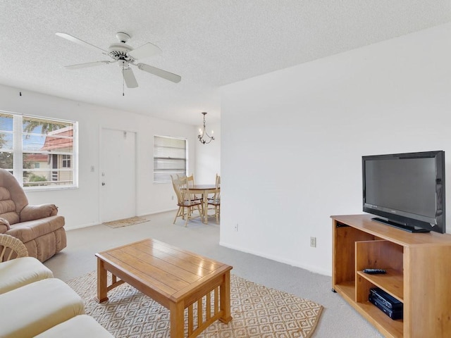 carpeted living area with a textured ceiling and ceiling fan with notable chandelier