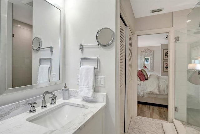ensuite bathroom featuring a stall shower, visible vents, wood finished floors, vanity, and connected bathroom