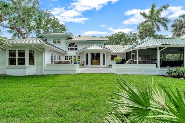 rear view of property featuring a lawn, a standing seam roof, a sunroom, and metal roof