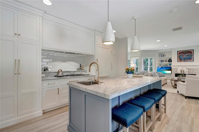 kitchen with open floor plan, light wood-style flooring, a sink, and white cabinetry