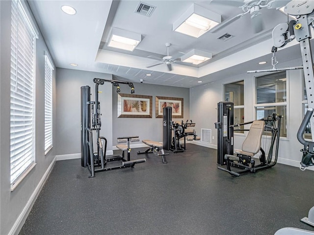 exercise room featuring recessed lighting, visible vents, baseboards, a ceiling fan, and a tray ceiling