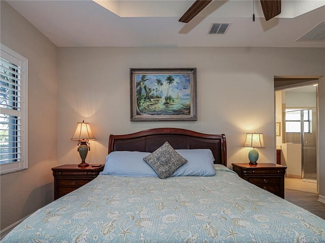 bedroom with a ceiling fan, visible vents, baseboards, and wood finished floors